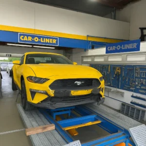 Yellow Ford Mustang on a Car-O-Liner frame machine during front bumper repair